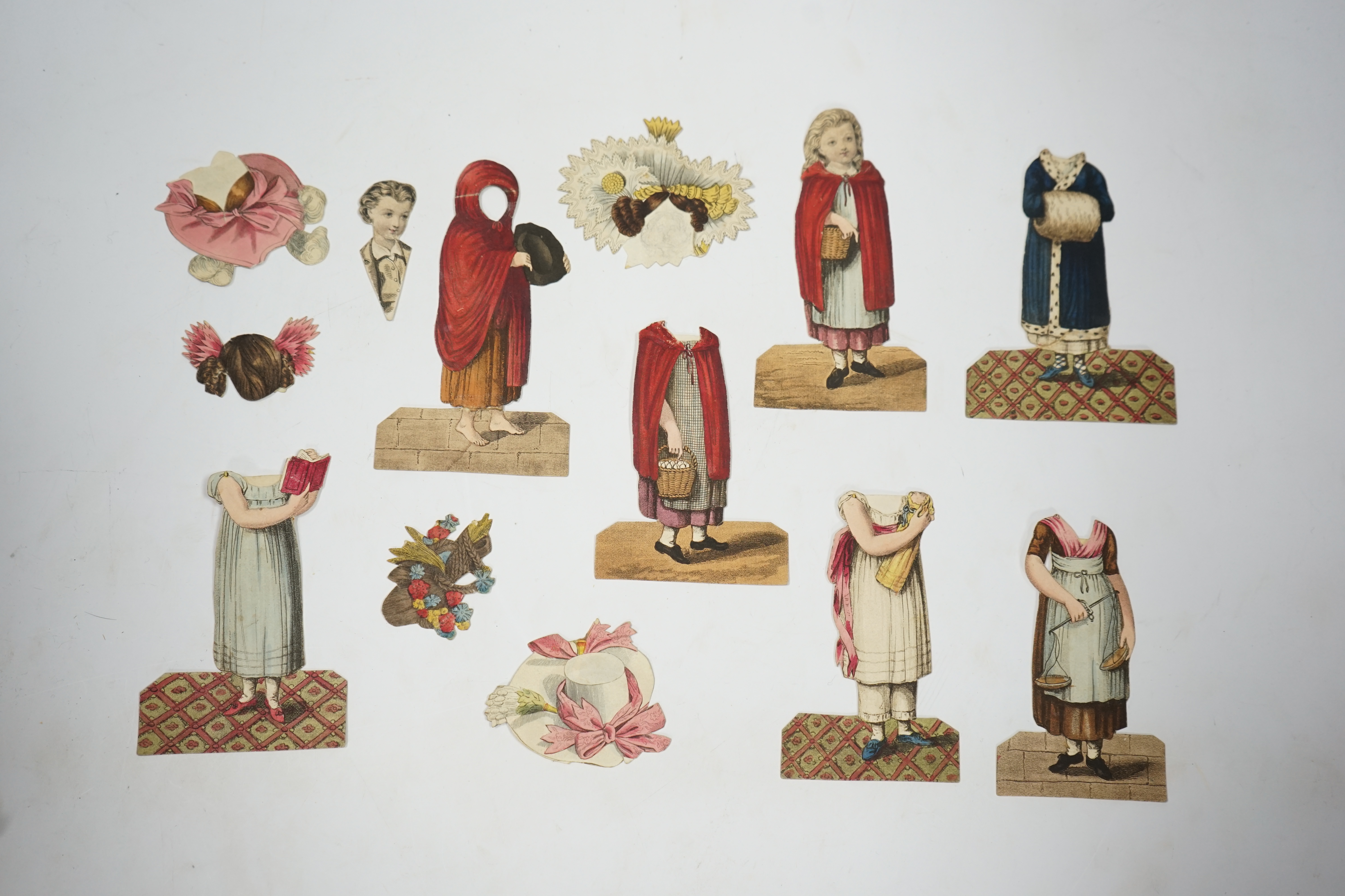 An early 19th century boxed Rudolph Ackermann La Poupee-Modele paper doll set, comprising of a double sided doll in lingerie with mahogany stand, six double sided gowns and four bonnets, together with eight similar figur